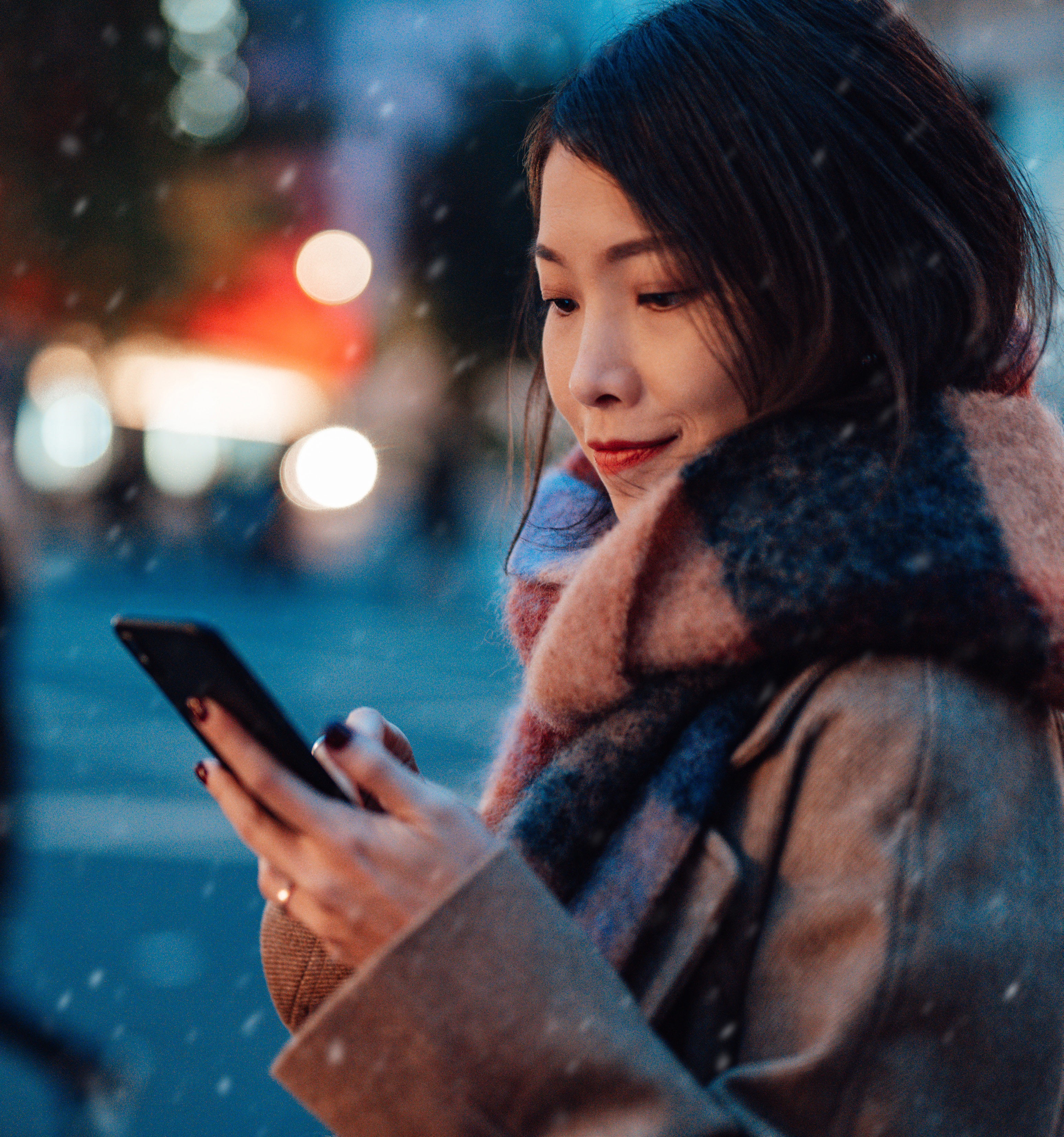 Woman using a phone against a soft, colorful city background